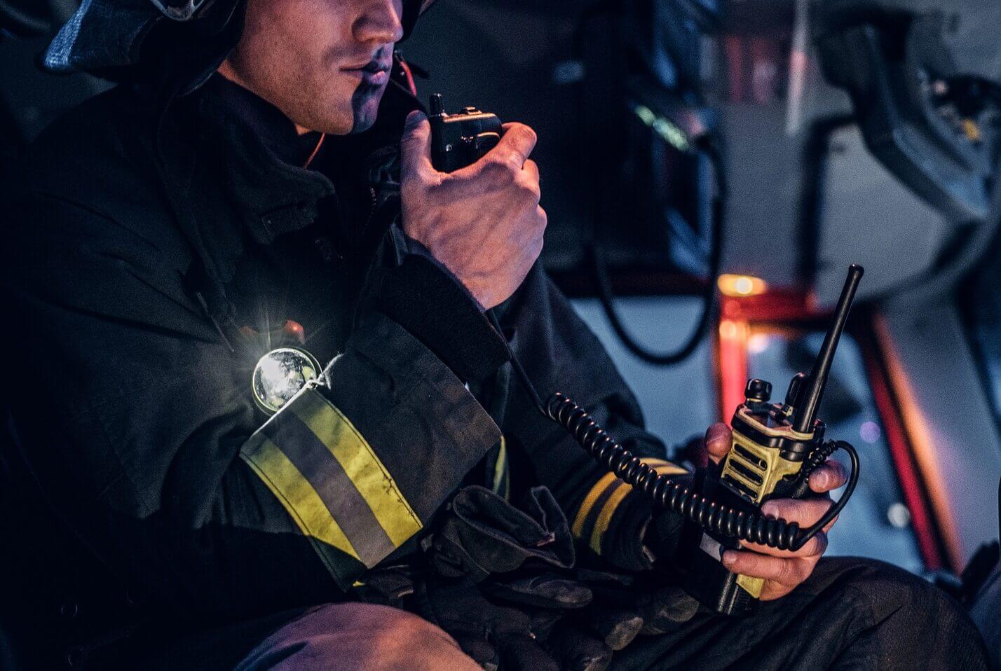 Fireman wearing protective uniform standing next to a fire engine in a garage of a fire department